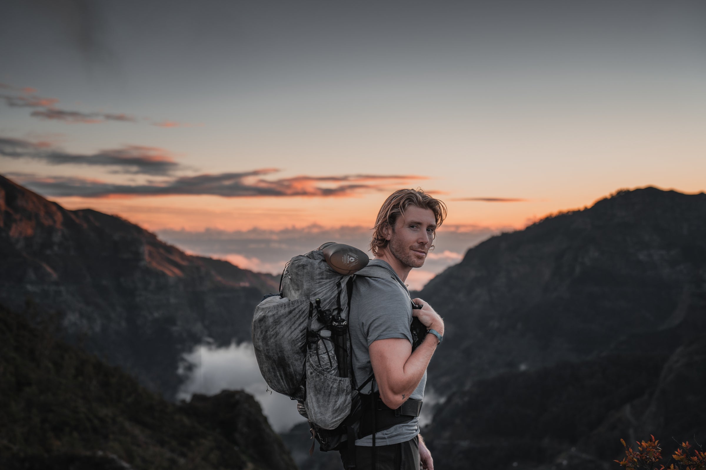 Man with a backpack at sunrise in the mountains