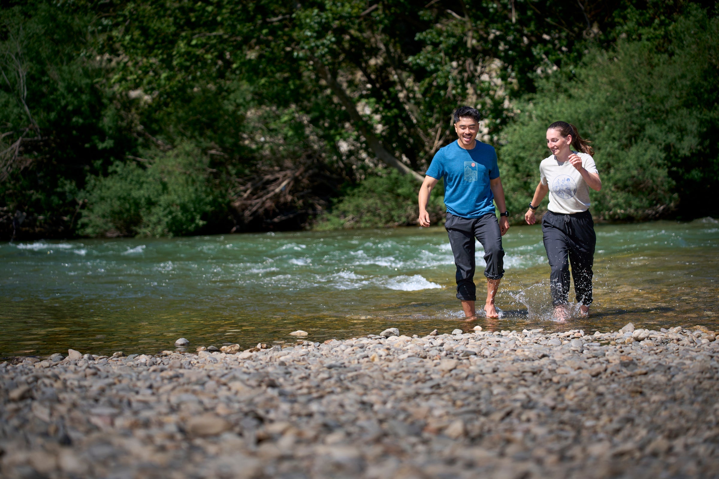 Two people walking along a riverbank