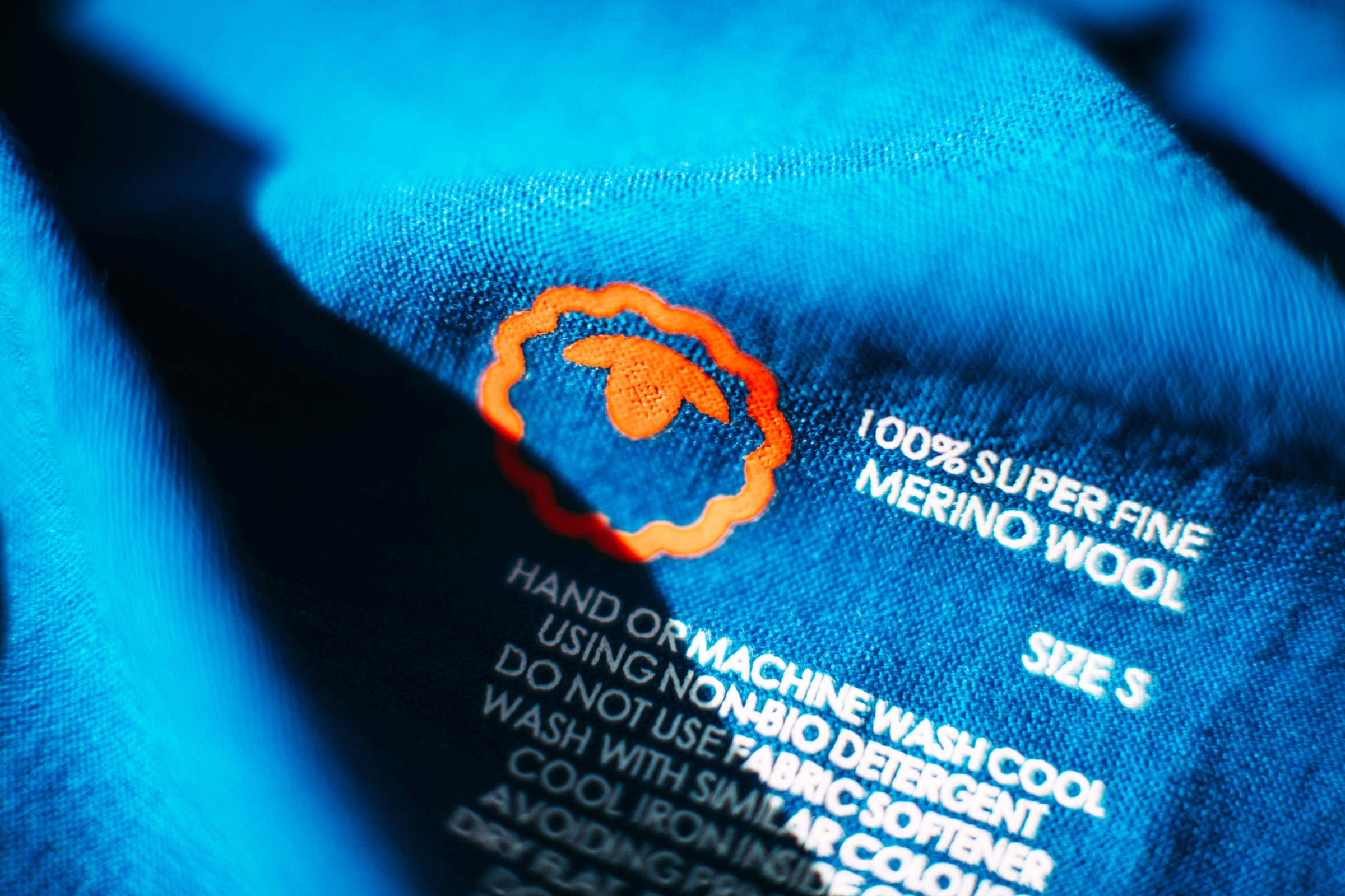 Gros plan sur une étiquette d’entretien en laine Merino superfine sur un tissu bleu