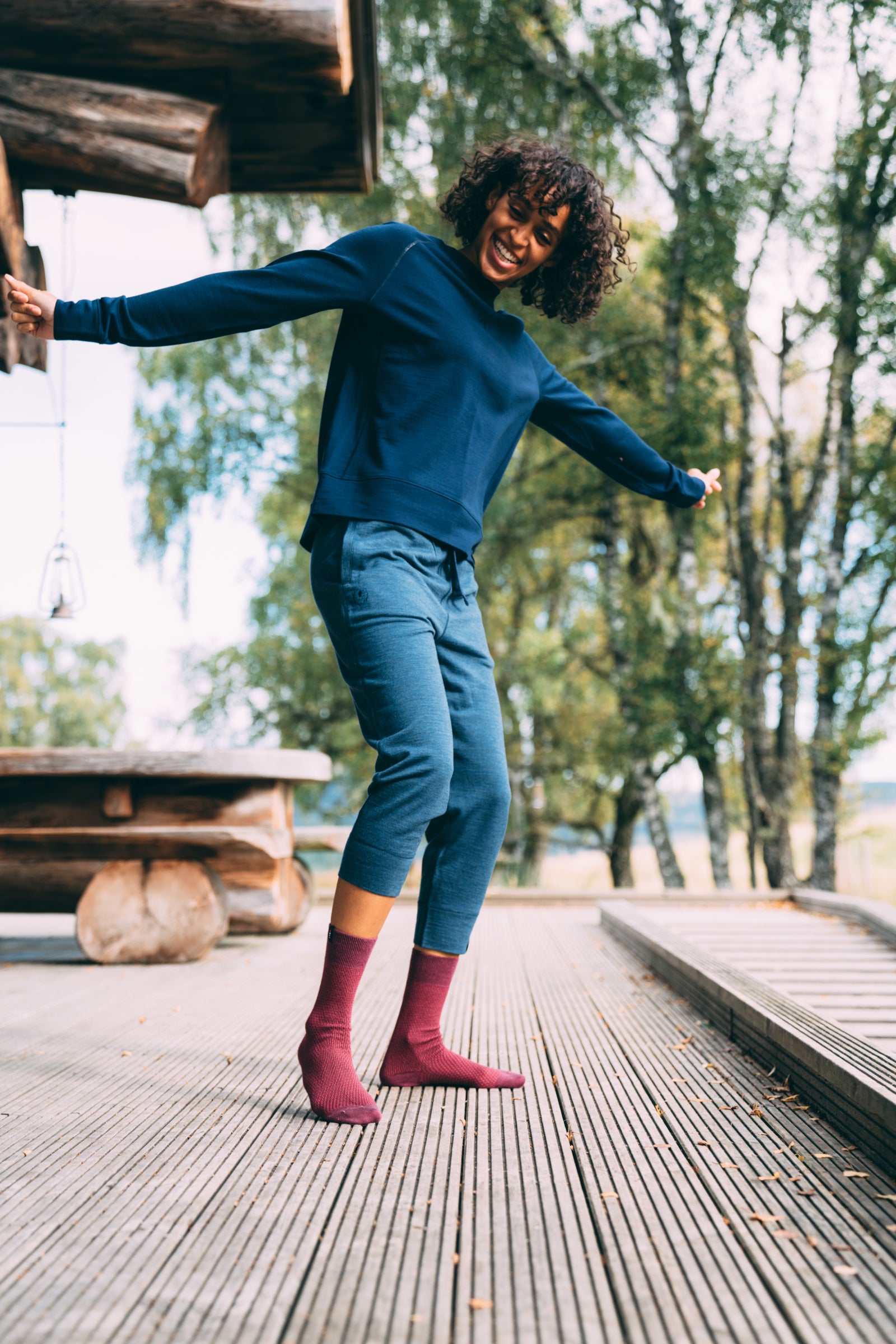Une femme en extérieur, souriante, qui danse sur une terrasse en bois