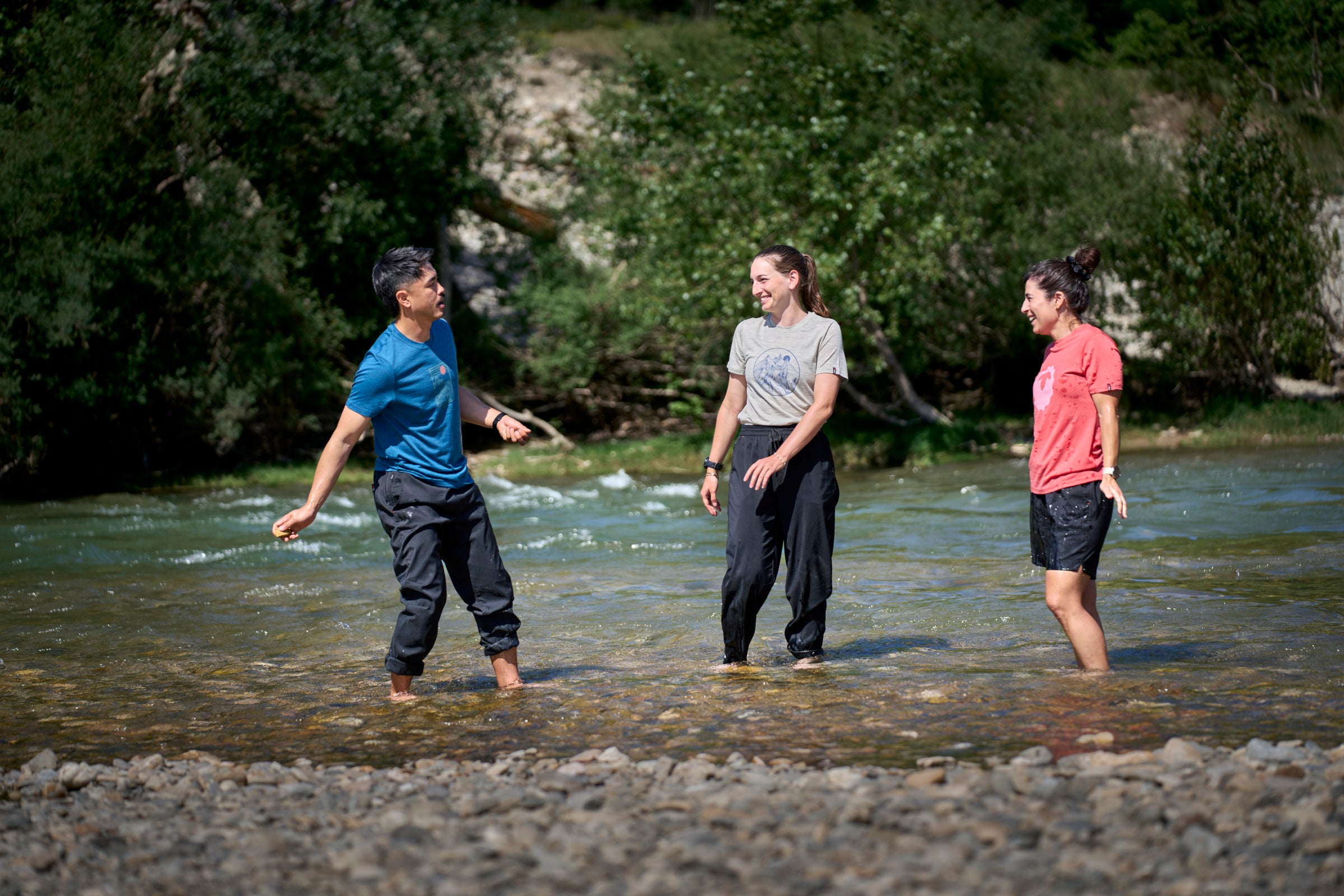 Three people standing in a shallow water body